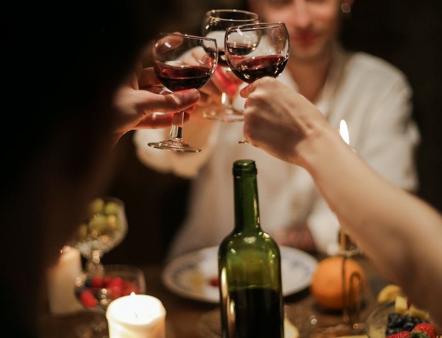 people holding wine glass with red wine
